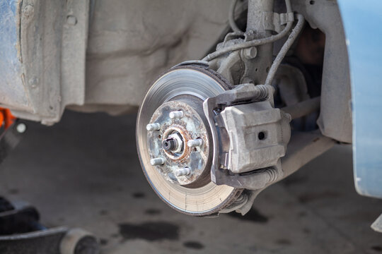 Disc brake of the vehicle for repair, in process of new tire replacement. Car brake repairing in garage.Suspension of car for maintenance brakes and shock absorber systems. Replacement of brake pads.