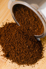 Close up macro texture of ground espresso coffee in metal holder on wooden table, morning drink ingredient preparation