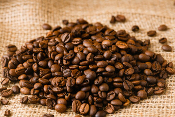 Close up texture of whole roasted coffee beans at sackcloth natural neutral background, morning drink routine
