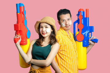 Happy Asian couple playing in the water for Songkran. They are holding a spray gun on isolated...