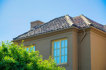 Modern house in middle class american suburbs with front or back yard trees with orange adobe rootop and chimney
