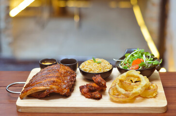 Grilled pork bbq ribs served with cherry tomatoes. basil and barbeque sauce on wooden cutting board over dark background. Close up