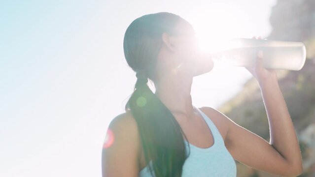 Runner, woman and drinking water in nature after fitness, running or morning cardio workout. Bottle, relax and thirsty Indian girl after healthy sport, run or endurance performance outdoors
