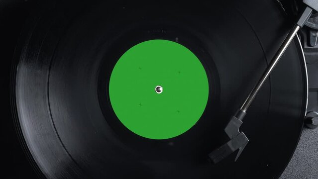 Close up of a vintage retro vinyl record with green sticker rotating. Top view. Old fashioned music. Needle gramophone. 4K ProRes