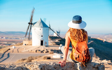 Rear view woman posing against windmills in Consuegra town. Spain - obrazy, fototapety, plakaty