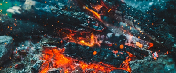 Vivid smoldered firewoods burned in fire closeup. Atmospheric background with orange flame of...