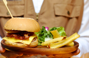 Delicious burgers, potato chips and salads on wooden trays in the restaurant.