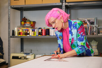 Tailor with pink hair and colorfull clothes drawing sewing patterns.