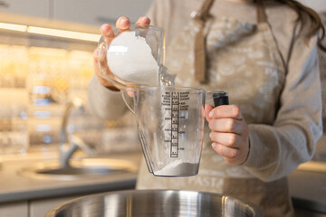 Girl, measuring flour with a measuring cup according to the recipe