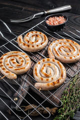 BBQ grilled spiral pork meat sausages on a grill. Black background. Top view