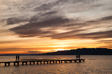 Fototapeta premium Silhouette of people looking at the dock at sunset in the Delta Ebro. Spain