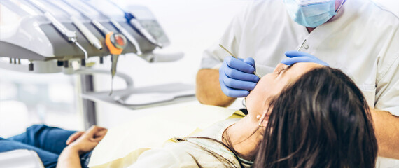 Dentist with patient in dental chair providing manipulations in oral cavity.