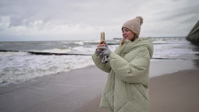 A woman on the seashore takes pictures on her phone