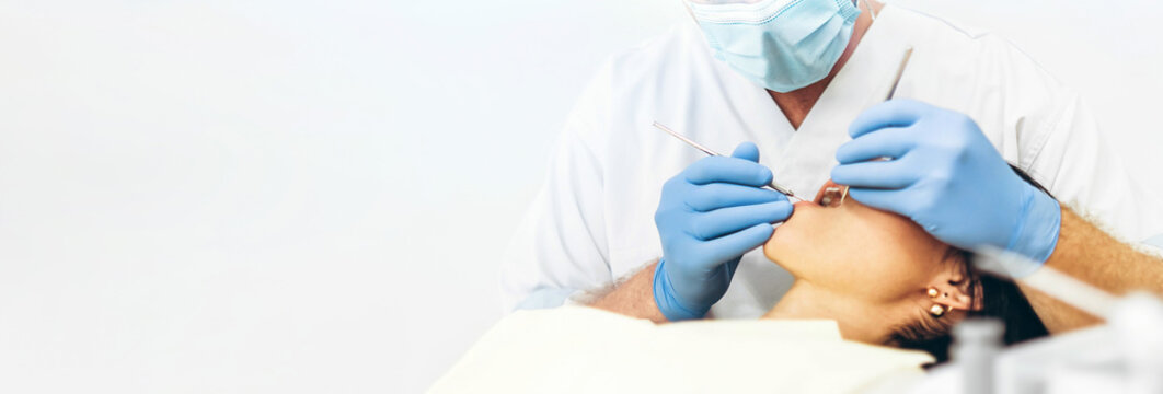 Dentist with patient in dental chair providing manipulations in oral cavity.