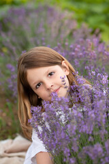 cute girl playing with a bouquet of lavender in a blooming field. Sunset. Attractive young female outdoors.