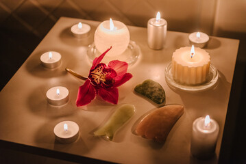 Details decor in spa salon. Gua sha tool. Candles, and orchid flowers on table. Facial massage for...