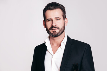 Portrait of handsome confident stylish hipster lambersexual model. Sexy modern man dressed in black elegant suit. Fashion male posing in studio, isolated on white