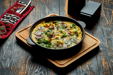 Menemen with eggs, Sujuk, green peppers, and spices served with bread in pan. Turkish breakfast