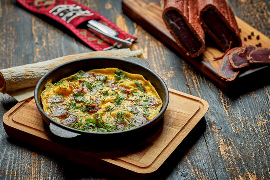 Menemen with eggs, Sujuk, green peppers, and spices served with bread in pan. Turkish breakfast