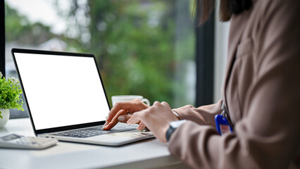 Close-up image of an Asian businesswoman working at her desk in the office, using laptop