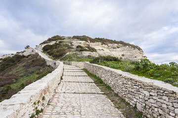 White rocks road leading to the top of the hill in Corsica near Bonifacio during a cloudy summer
