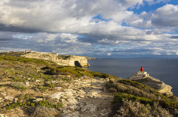 Fototapeta na wymiar Cliffs seascape with a red lighthouse at the golden hour in Corsica near to Bonifacio during summer
