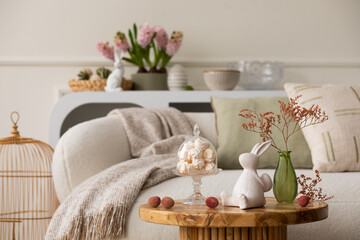 Warm and cozy composition of easter living room interior with coffee table, white sofa, colorful...