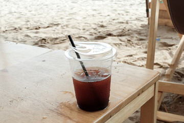 iced coffee and sea, Iced black coffee americano in take away cup (plastic glass) on the beach background.