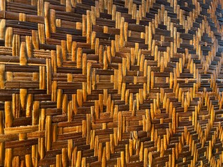 Background and texture of woven bamboo with diamond pattern on a building wall.