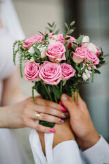 Obraz na płótnie Canvas Bouquet of white and pink of roses in bride's hands. Newlywed couple. Groom and bride together. Perfect wedding couple holding a luxury bouquet of flowers. Close up.