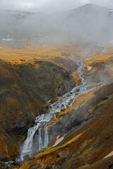 Terre de feu volcanique aux tons ocre avec cour d'eau coulant au milieu des montagne d'Islande en hivers 