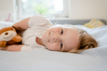 Adorable little girl holding her stuffed toy and looking at the camera