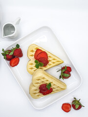 Selective focus of Waffles garnished with strawberries on a white plate with white background