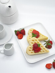 Selective focus of Waffles garnished with strawberries on a white plate with white background
