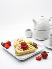 Selective focus of Waffles garnished with strawberries on a white plate with white background