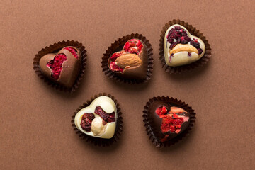 chocolate sweets in the form of a heart with fruits and nuts on a colored background. top view with space for text, holiday concept