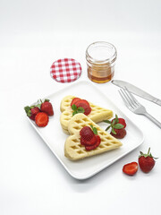 Selective focus of Waffles garnished with strawberries on a white plate with white background