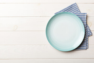 Top view on colored background empty round blue plate on tablecloth for food. Empty dish on napkin...