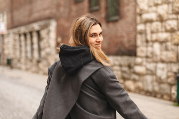Young beautiful smiling hipster woman in trendy outfit. Sexy carefree woman posing on the street. Cheerful and happy girl wear grey suit and black hoodie turn around. Lifestyle, female beauty concept.