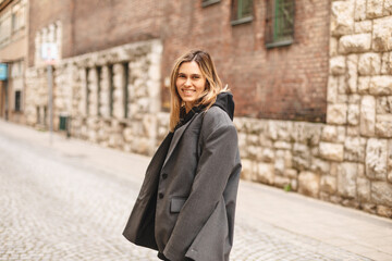 Young beautiful smiling hipster woman in trendy outfit. Sexy carefree woman posing on the street. Cheerful and happy girl wear grey suit and black hoodie turn around. Lifestyle, female beauty concept.