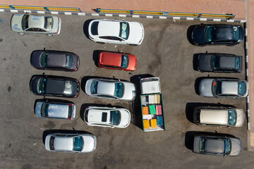 Aerial top view of the open space parking lots with lots of car and a truck that full of colourful container