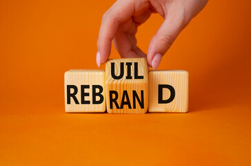 Rebuild and Rebrand symbol. Businessman hand turns wooden cubes and changes the word to Rebrand to Rebuild. Beautiful orange background. Rebuild Rebrand and Business concept. Copy space