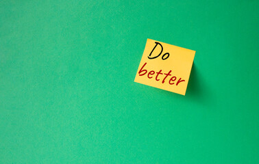 Do better symbol. Orange steaky note with concept words do better. Beautiful green background. Business and Do better concept. Copy space.