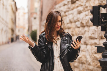 Explain wtf message mean. Portrait of frustrated questioned and annoyed young woman arguing over bad news shrugging spread hands in dismay sideways being displeased walking on the street in city.