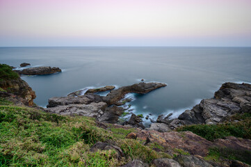 Landscape of blue sea, mountains and textured rocks. Hazy dreamy sky. Longdong is a paradise for viewing sea views in the north of Taiwan.