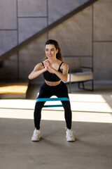 Fototapeta premium Young woman during her fitness workout at home with rubber resistance band