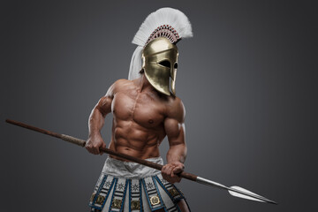 Shot of greek athlete with perfect body and spear dressed in plumed helmet.
