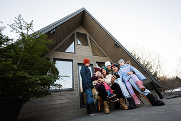Large family with four children sit on terrace off grid tiny house in the mountains looking on...