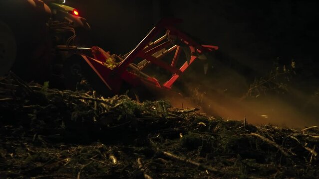 Forest mulcher processes tree remains after bark beetle infestation at night. heavy equipment. closeup