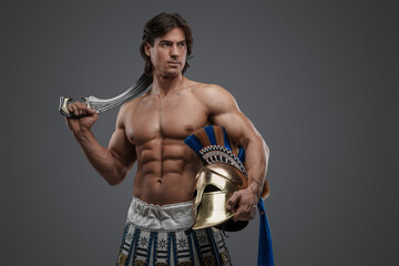 Shot of isolated on grey background muscular warrior with sword and plumed helmet.